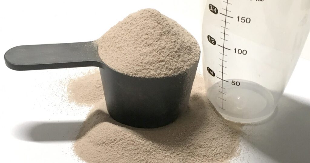 計量スプーンとシェイカー横のプロテインパウダー