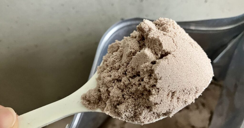 スプーンですくったチョコレート味のプロテインパウダー